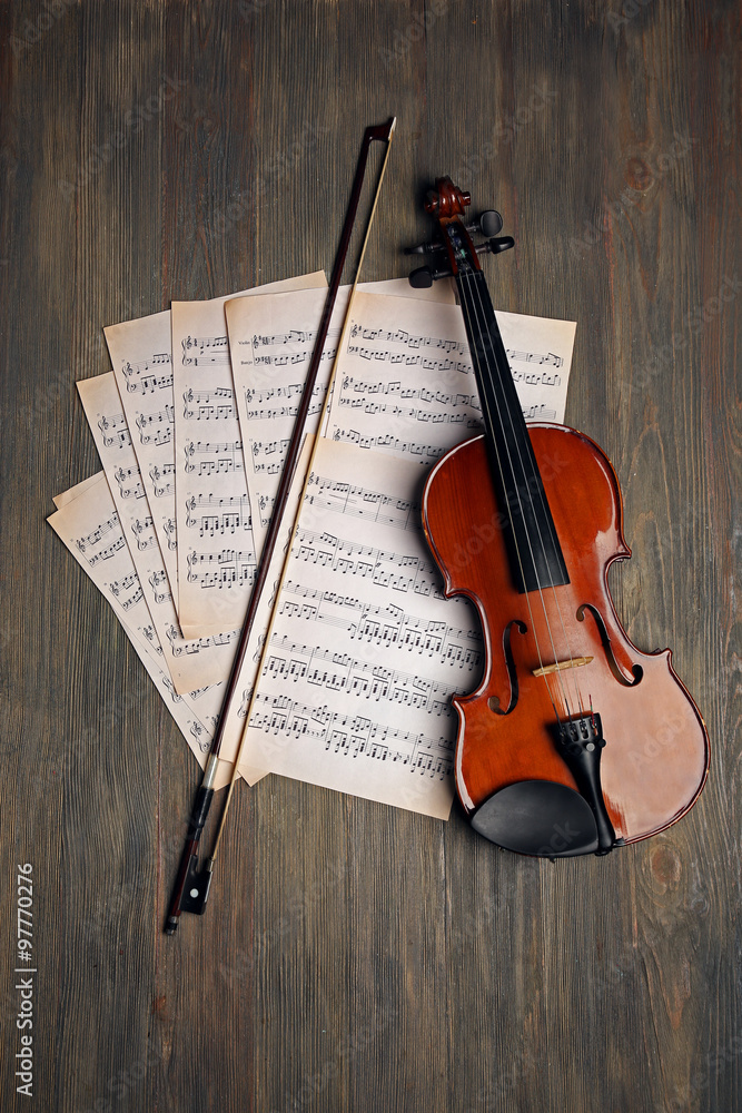 Wall mural Violin and music papers on wooden background