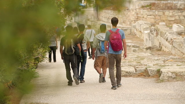 Young men with rucksacks go sightseeing around ruins of ancient Agora of Athens