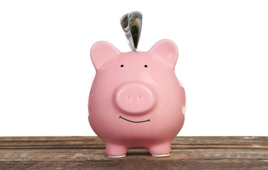 Piggy bank with banknote on wooden table, isolated on white