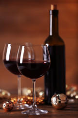 Red wine and Christmas ornaments on wooden table on wooden background