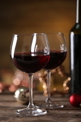 Red wine and Christmas ornaments on wooden table on wooden background