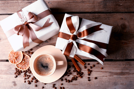Beautiful gift, cup with coffee and coffee grains on wooden background