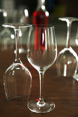 Construction of empty wine glasses and bottle on wooden table against blurred background