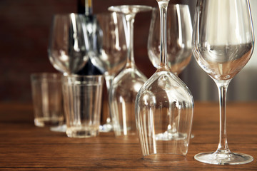 Construction of empty wine glasses on wooden table against blurred background