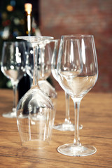 Construction of empty wine glasses and bottle on wooden table against blurred background