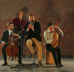 Fototapeta premium Man's musical band on brick wall background in the studio