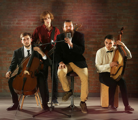 Fototapeta premium Man's musical band on brick wall background in the studio