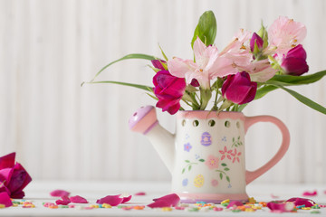 bouquet of bright flowers in watering can on wooden background