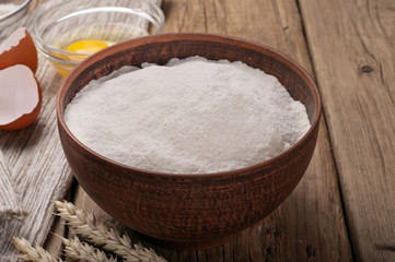 Flour in a clay bowl with ears of wheat