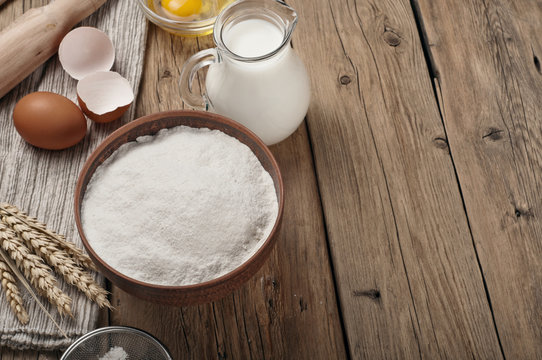 Flour, egg, milk on wooden table rustic kitchen