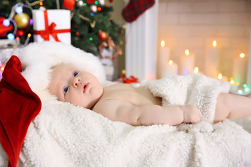 Cute naked baby in red hat on the warm blanket, close up