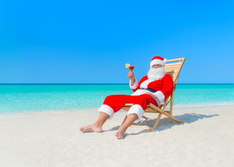 Christmas Santa Claus with cocktail on deck chair at beach