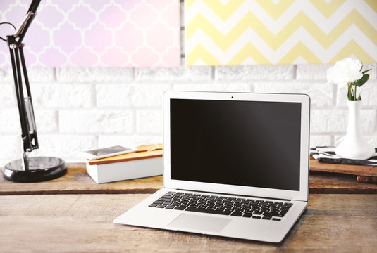 Modern lamp and laptop on table on brick wall background