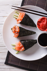 Salmon temaki sushi, pickled ginger and sauce closeup. vertical top view
