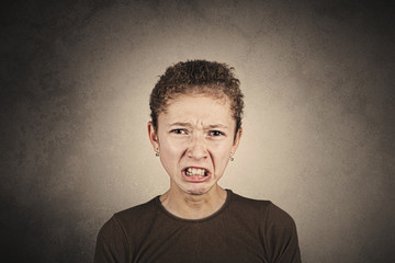 Portrait of little girl disgusted by something over grey background.Negative expression.