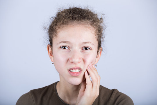 Portrait Of A Young Girl With Toothache Over White Background.Child Toothache With Sensitive Tooth Ache Problem Touching On Face The Part With Pain.