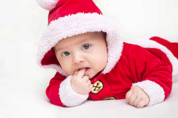 Happy baby lying on tummy wearing a red and white Christmas Santa suit.