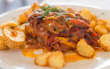 Fish with tomato sauce and fried potatoes.