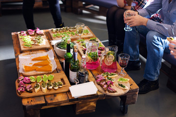 Company of friends eating together in the restaurant. Wooden tray of appetizers at a banquet on a...