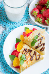 Pancakes with sliced strawberries and orange