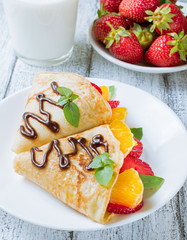 Pancakes with sliced strawberries and orange