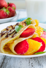 Pancakes with sliced strawberries and orange