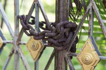 A chain link fence locked with a rusty chain and a padlock
