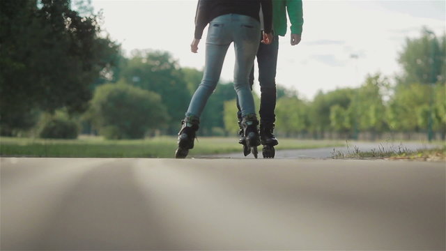 Young attractive couple rollerblading and doing tricks with skates in park on a summer day