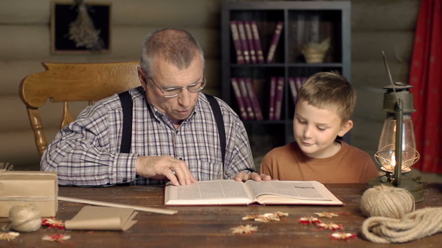Grandfather and grandchild reading a book together 