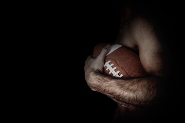 Side view of shirtless rugby player holding ball