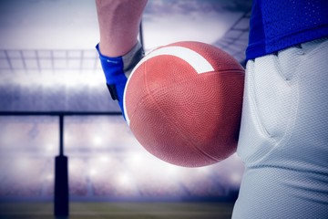Composite image of american football player holding ball
