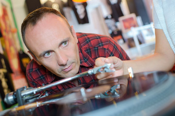 man looking at record player