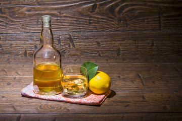 Bottle with a glass with whiskey and lemon are on the napkin