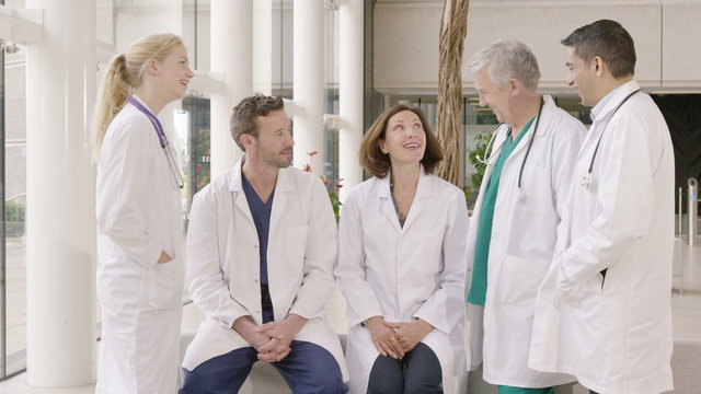 Team of doctors having a discussion in hospital turn to smile at camera