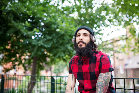 Young tattooed man portrait relaxing in a park in Shoreditch borough. London.