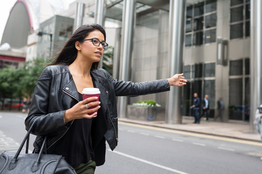 Young mixed race businesswoman portrait looking for a taxi outdoors in Canary Wharf in London.
