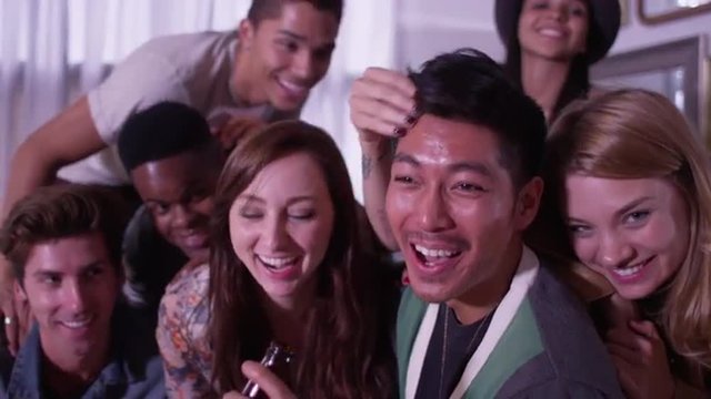 Multi ethnic group of fun loving young hipster friends smiling at camera and laughing having fun
