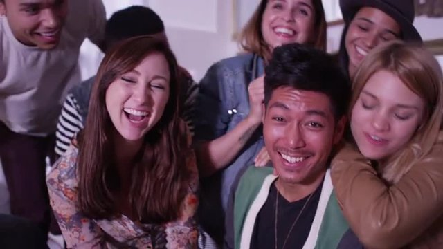 Mixed race group of fun loving young hipster friends smiling at camera and laughing having fun