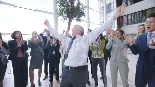  Self confident businessman cheering and giving high fives to colleagues