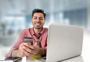 happy attractive businessman working at office desk using mobile phone