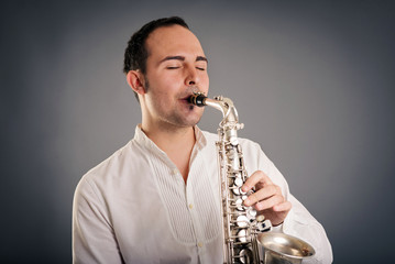 Saxophone player man isolated against dark background. Close up