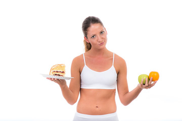 verzweifelte frau hält obst und ein stück kuchen in der hand