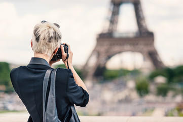 Young woman with camera taking a photo in front of the Eiffel To