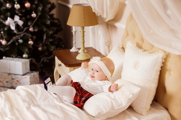 happy baby girl is laughing in bedroom at Christmas tree 