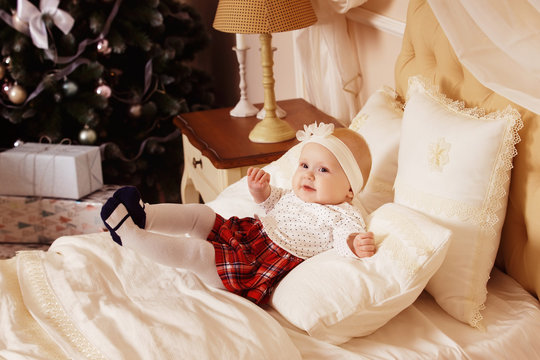 happy baby girl is laughing in bedroom at Christmas tree 
