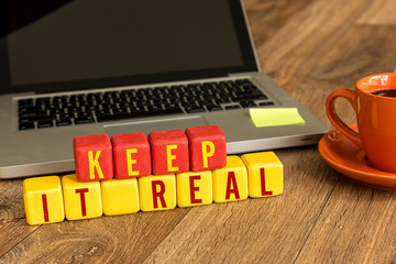 Keep it Real written on a wooden cube in a office desk