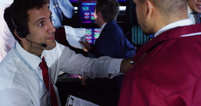  City stockmarket trader at work, in a chaotic trading room with lots of other brokers. Shot on RED Epic.