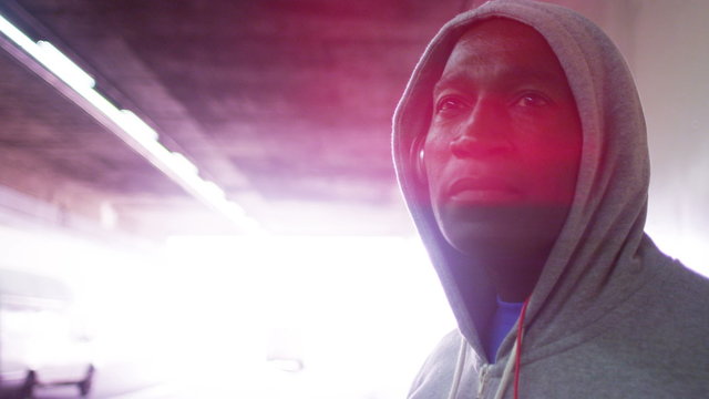  Portrait of athletic black male in a hooded sweatshirt, in urban environment. Could be an athlete in training or a suspicious character.