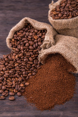 Кофейные зерна и молотый кофе в мешках на темном фоне крупным планом