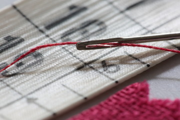 Fototapeta na wymiar hand sewing needle with red thread bobbin 